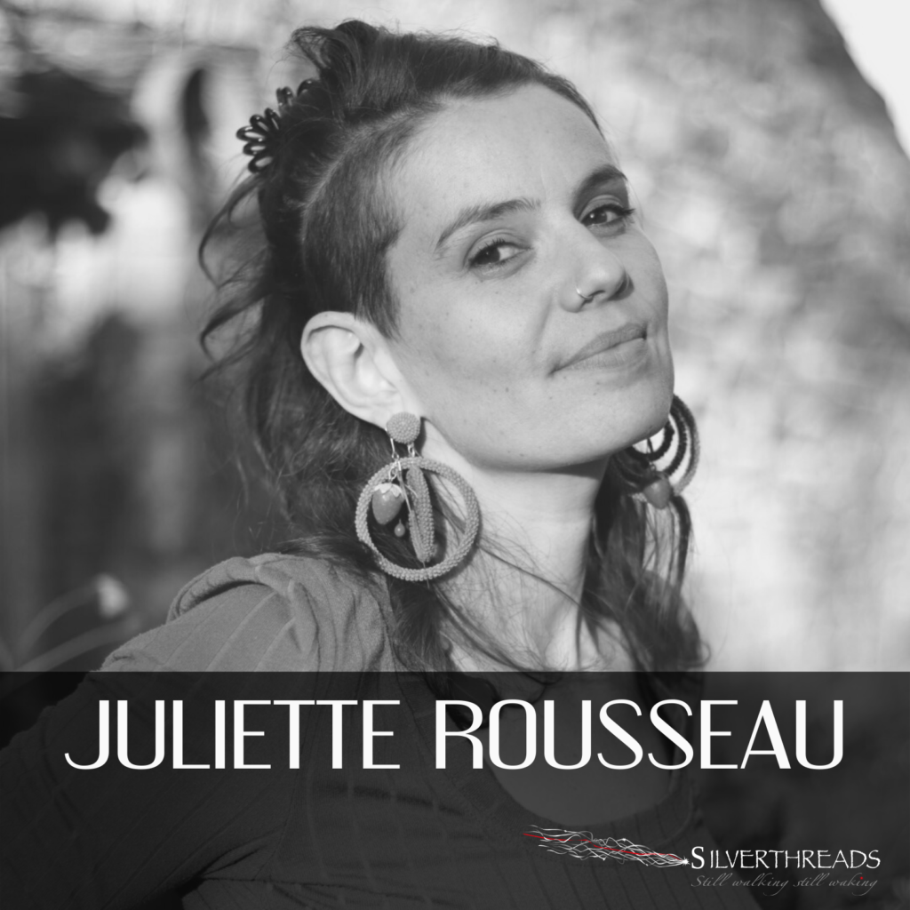 Black and white photo of Juliette, half-smiling into the camera, wearing hair half up and large round earrings. There is text that says, “Juliette Rousseau” and the logo for Silver Threads in the bottom right corner.