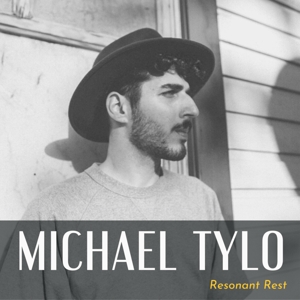A black and white photo of Michael Tylo standing in front of a building, looking to the right. They wear a light T-shirt and a dark, wide-brimmed hat. There is text that reads “Michael Tylo” and “Resonant Rest.”