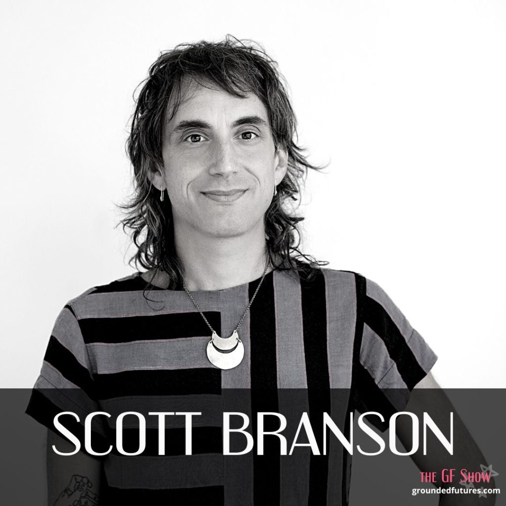A Black and white photo of Scott Branson. They are smiling and wearing a striped top with a moon pendant On the bottom right it says, the GF Show. groundedfutures.com